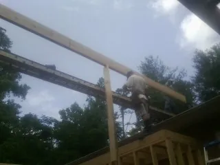 Carpenter setting a ridge beam over a new addition frame — Ice Dam Removal by Roofing Brothers in Friedens