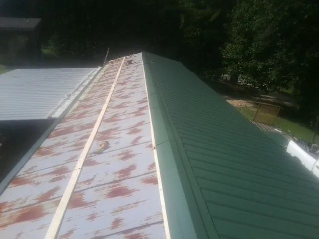 Old rusted panels beside newly installed green metal roofing — Wind Damage Roof Repair by Roofing Brothers in Friedens