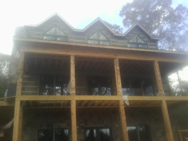 Dormers and porch framing on a large log home under construction — Roof Coating work by our crew in Friedens
