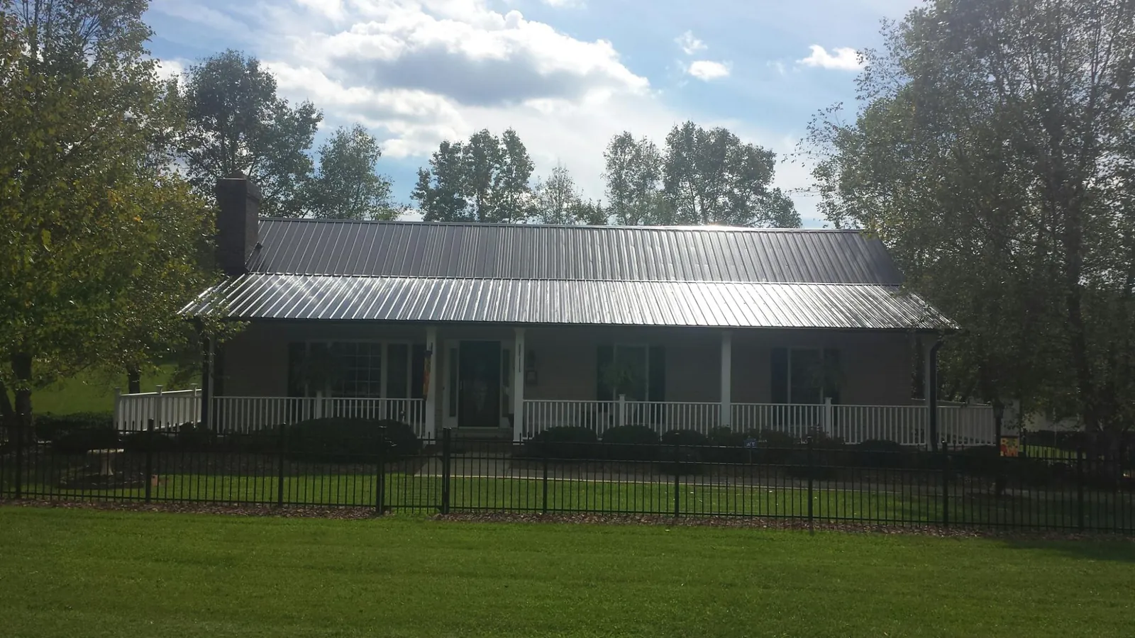 Gray metal roof on a brick ranch with a full width front porch — Gutter Guard Installation work by our crew in Friedens