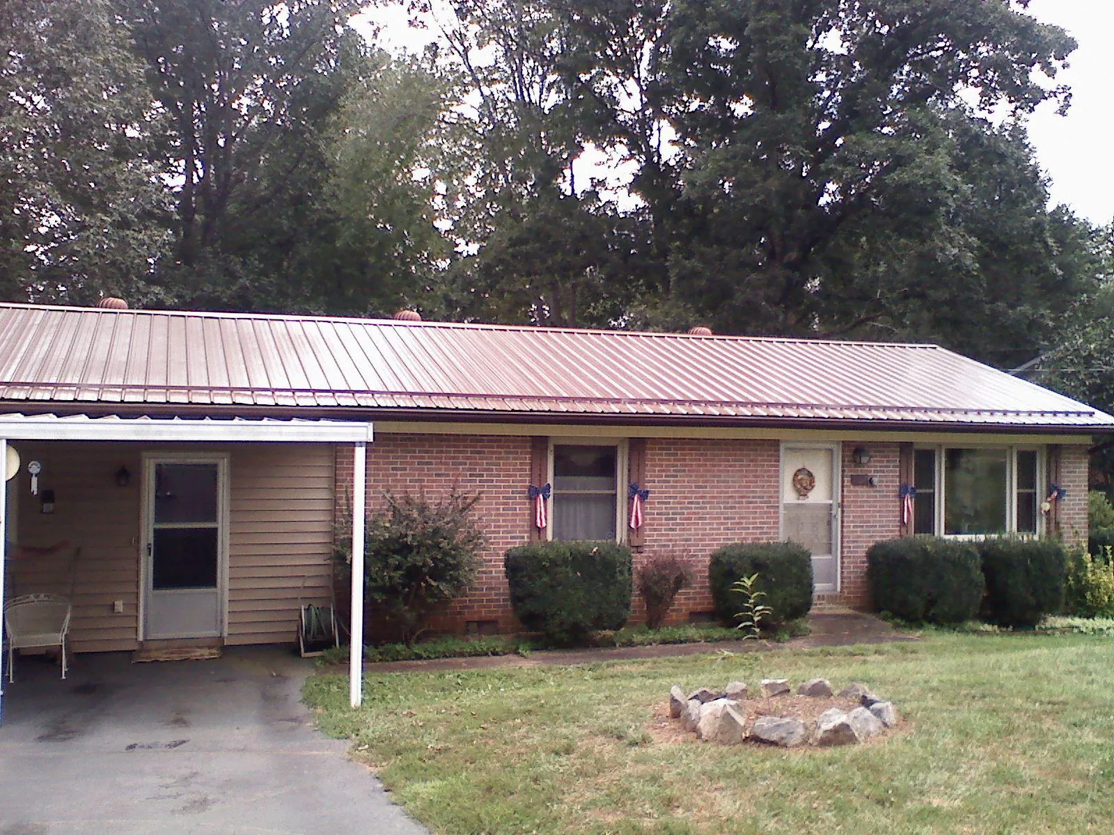 Bronze metal roof and carport on a brick ranch home — Roof Repair work by our crew in Friedens
