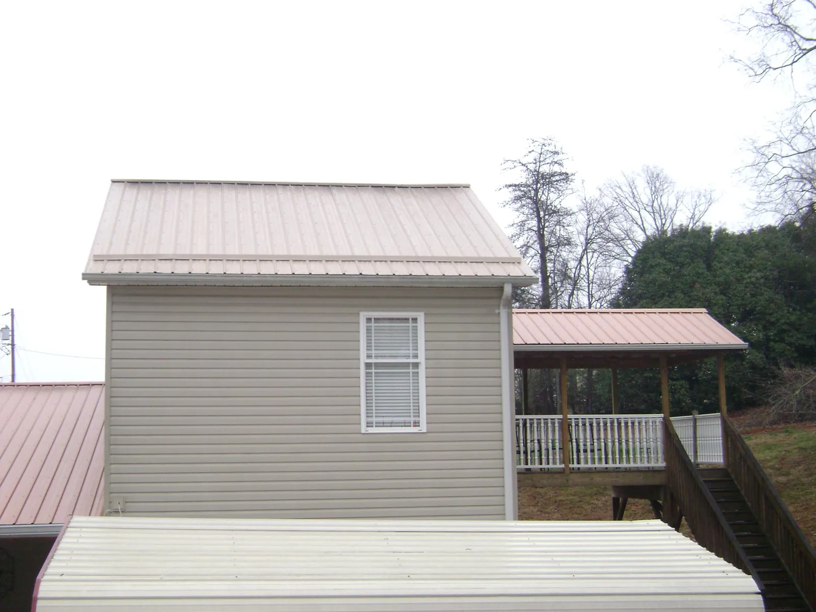 Tan metal roofs on a two story addition and attached porch, from a Roof Replacement job in Friedens