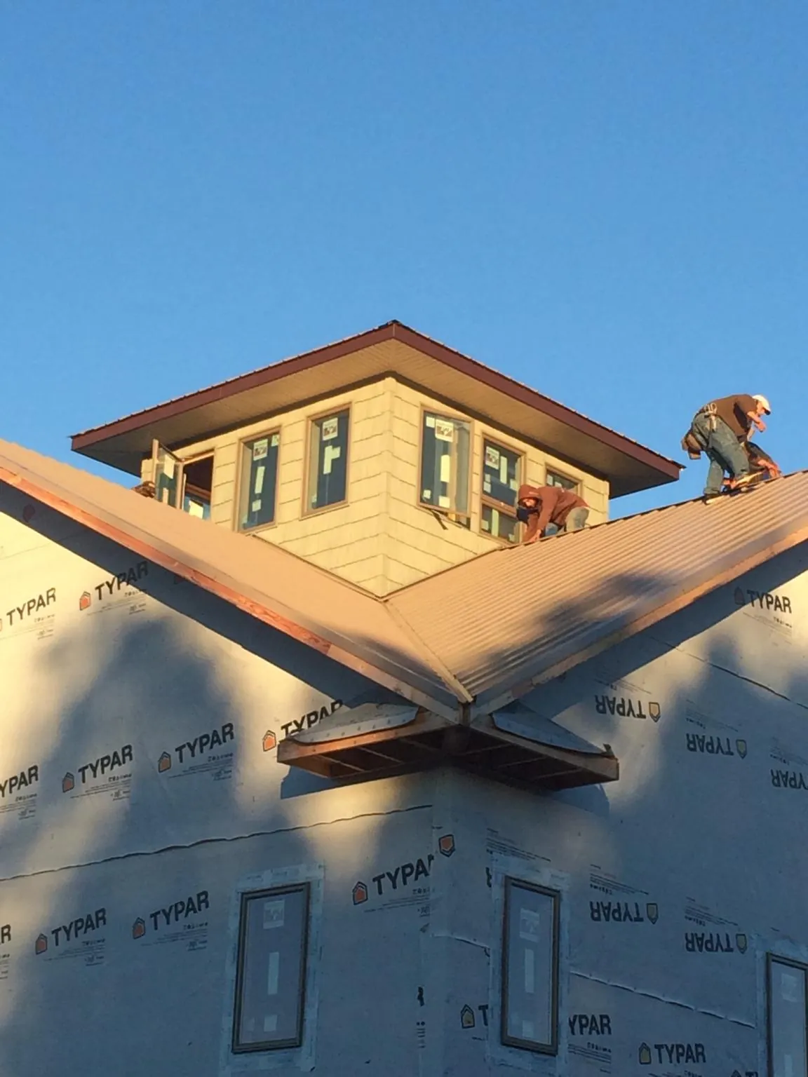 Roofers working around a rooftop cupola on a new metal roof at sunset — Roof Waterproofing in Friedens by Roofing Brothers